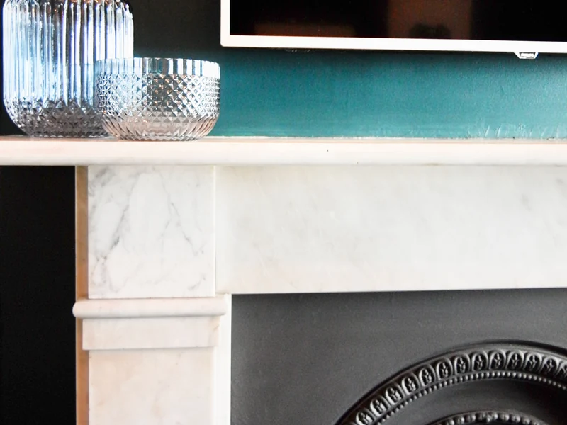 White marble fireplace surround with glass jars on the mantel